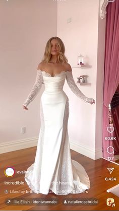 a woman in a white wedding dress standing on a wooden floor with her arms outstretched