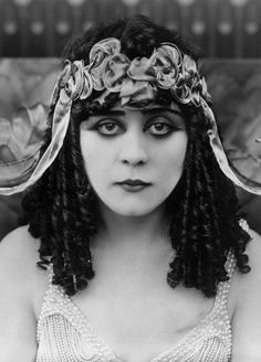 a black and white photo of a woman with long hair wearing a headdress