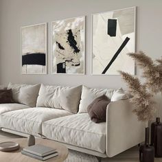 a living room with white couches and paintings on the wall above them, along with a coffee table