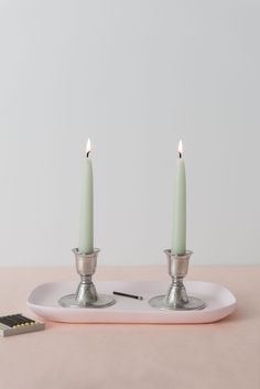 two candles sitting on top of a white plate