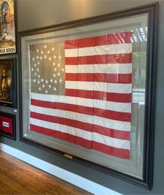 an american flag is displayed in a glass case on the wall above a wooden floor