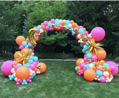 an arch made out of balloons in the grass