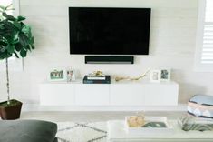 a flat screen tv mounted on the wall above a white entertainment center in a living room