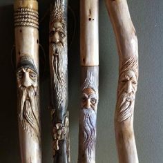 four carved wooden flutes with faces on them