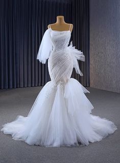 a white wedding dress on display in front of a curtain