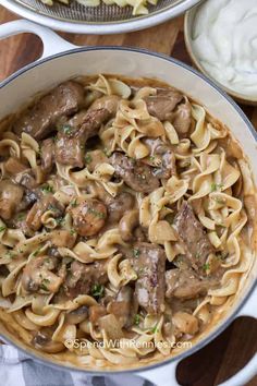 pasta with mushrooms and sauce in a pan on a wooden table next to other dishes