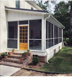 a screened porch with steps leading to the front door and patio area, along with potted plants