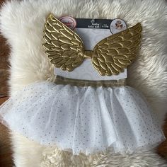 a white dress with gold angel wings on it and a card in the back pocket