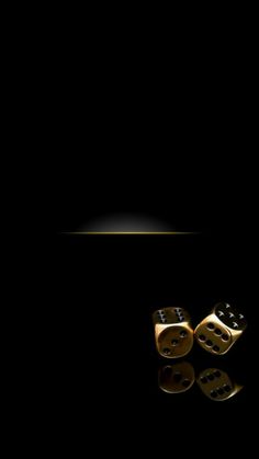 two gold dices sitting on top of each other in front of a black background