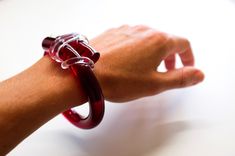 "The Knot Bangle is a contemporary design inspired by its symbolism of love, union and the concept of eternal and unbreakable love. Each piece is made by hand and it's colors can brighten any outfit! This one is like red wine color!🍷 Size: The inside diameter is about 2.5 inches but it can be customized to any size you need. You may specify your size on the \"Notes\" section during check out. 100% Acrylic | Handcrafted | Made in Miami" Bold Adjustable Bracelets As Gift, Bold Bangle Jewelry As A Gift, Bold Bangle Jewelry For Gifts, Bold Bangle Jewelry Gift, Modern Red Jewelry For Gifts, Unique Red Bracelet As Gift, Unique Red Bracelet For Gift, Modern Red Bangle Bracelets, Modern Red Bangle Bracelet