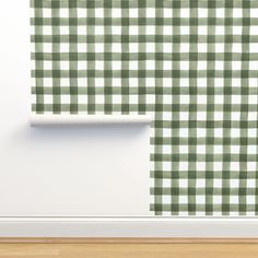 a green and white checkered wallpaper in an empty room with wood flooring