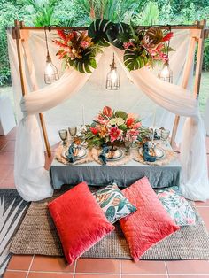 a table set up with flowers and greenery for a wedding reception in the jungle