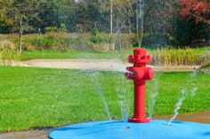 a red fire hydrant spewing water onto a blue blanket in the yard