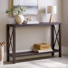 a table with books and a vase on it in front of a painting hanging on the wall