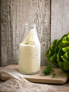 lettuce and ranch dressing in a glass bottle on a cutting board next to a head of lettuce