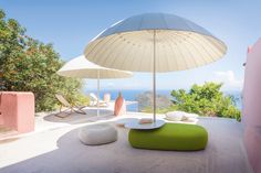 an umbrella sitting on top of a white table next to a green ottoman and chair