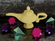 a crocheted teapot with several small beads around it