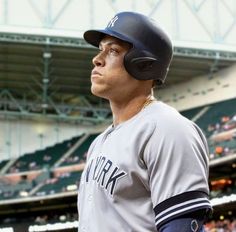 a baseball player standing in the batters box with his helmet on and looking off to the side