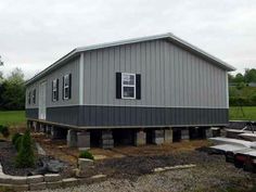 a large metal building sitting on top of a gravel lot next to a green field