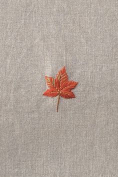 a red leaf is embroidered on the back of a gray shirt