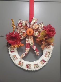 a wreath hanging on the wall with red and yellow flowers attached to it's sides