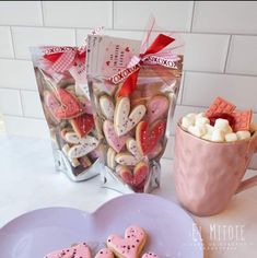 heart shaped cookies and marshmallows on a plate next to a bag of valentine's day treats