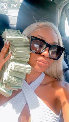 a woman sitting in the back seat of a car holding stacks of money