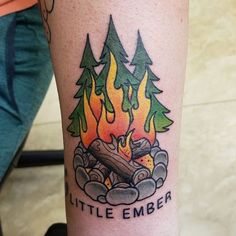 a person with a tattoo on their arm that has a campfire and firewood in it