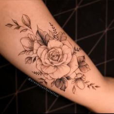 a woman's arm with flowers and leaves on it