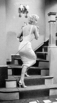 a woman in a dress is walking down the stairs with her hand on her hip