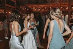 a group of women standing around each other on a dance floor at a wedding reception