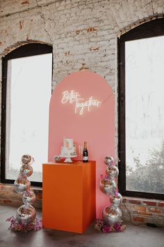 an orange table with balloons and bottles in front of two large windows that say better together