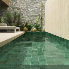 an indoor swimming pool with green tiles on the floor and walls, surrounded by greenery