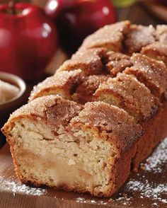 a loaf of cinnamon apple bread sitting on top of a wooden cutting board next to apples