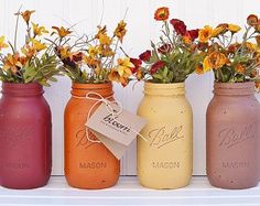 three painted mason jars with flowers in them