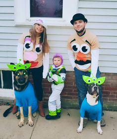 a man and woman with two small children wearing costumes, standing in front of a house