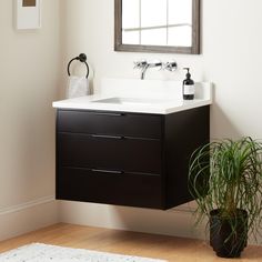 a bathroom with a sink, mirror and potted plant on the floor next to it