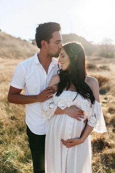 a man and woman are standing in the grass