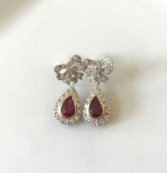 Metal: 14kt White Gold Stone: Diamond And Ruby Shape: Round And Pear-shape Ruby Weight : 1.00 ctw Diamond Weight: .52 ctw Type Of Backing: Post Weight of entire piece: 5.60 grams Dimensions of Earrings From Top To Bottom: 24.22mm Customizable: We can custom make these earrings (and its matching necklace) with any gems and metals of your choice. Please inquire if interested. Matching Necklace: https://www.etsy.com/listing/549448744/vintage-style-14k-white-gold-ruby-and?ref=shop_home_active_2 Luxury Hallmarked Pear-shaped Diamond Earrings, Platinum Pear-shaped Diamond Earrings For Formal Occasions, Ruby Gemstone Diamond Earrings For Formal Occasions, Formal Ruby Gemstone Diamond Earrings, Wedding Ruby Earrings With Brilliant Cut, Ruby Earrings With Brilliant Cut For Wedding, Hallmarked Pear-shaped Diamond Earrings For Anniversary, Pear-shaped Hallmarked Diamond Earrings For Anniversary, Pear-shaped Diamond Earrings For Formal Events