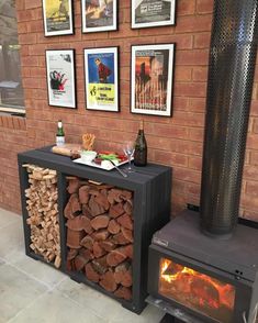 a fire place with logs stacked next to it and framed pictures on the wall behind it