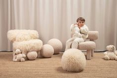 a little boy sitting in a chair surrounded by stuffed animals and balls on the floor