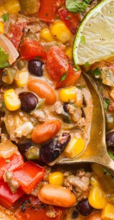 a spoon full of mexican soup with corn, tomatoes, black beans and cilantro