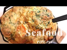 a close up of food in a pan on a table with a spoon and the words seafood pot pie