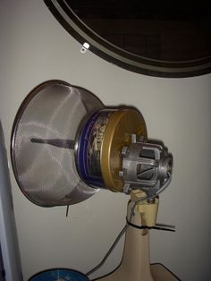 a close up of a metal object on top of a wooden table next to a white wall