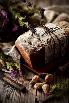 a loaf of bread sitting on top of a wooden table next to flowers and nuts