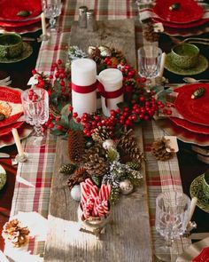 a christmas table setting with candles, candy canes and pine cones