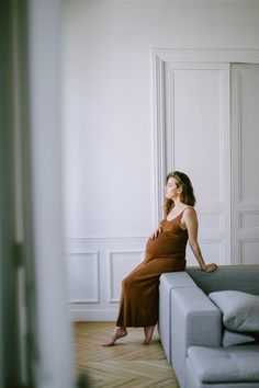 a woman sitting on top of a couch in a living room next to a wall