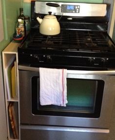 a tea pot is sitting on top of an oven with a towel hanging from it