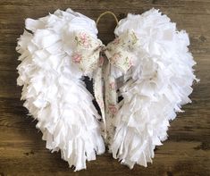 white angel wings with pink flowers and bows on wood floored area, top view