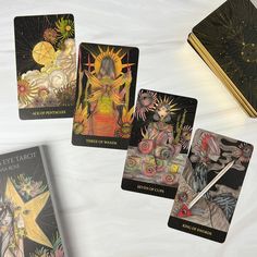 four tarot cards on a table with an open book